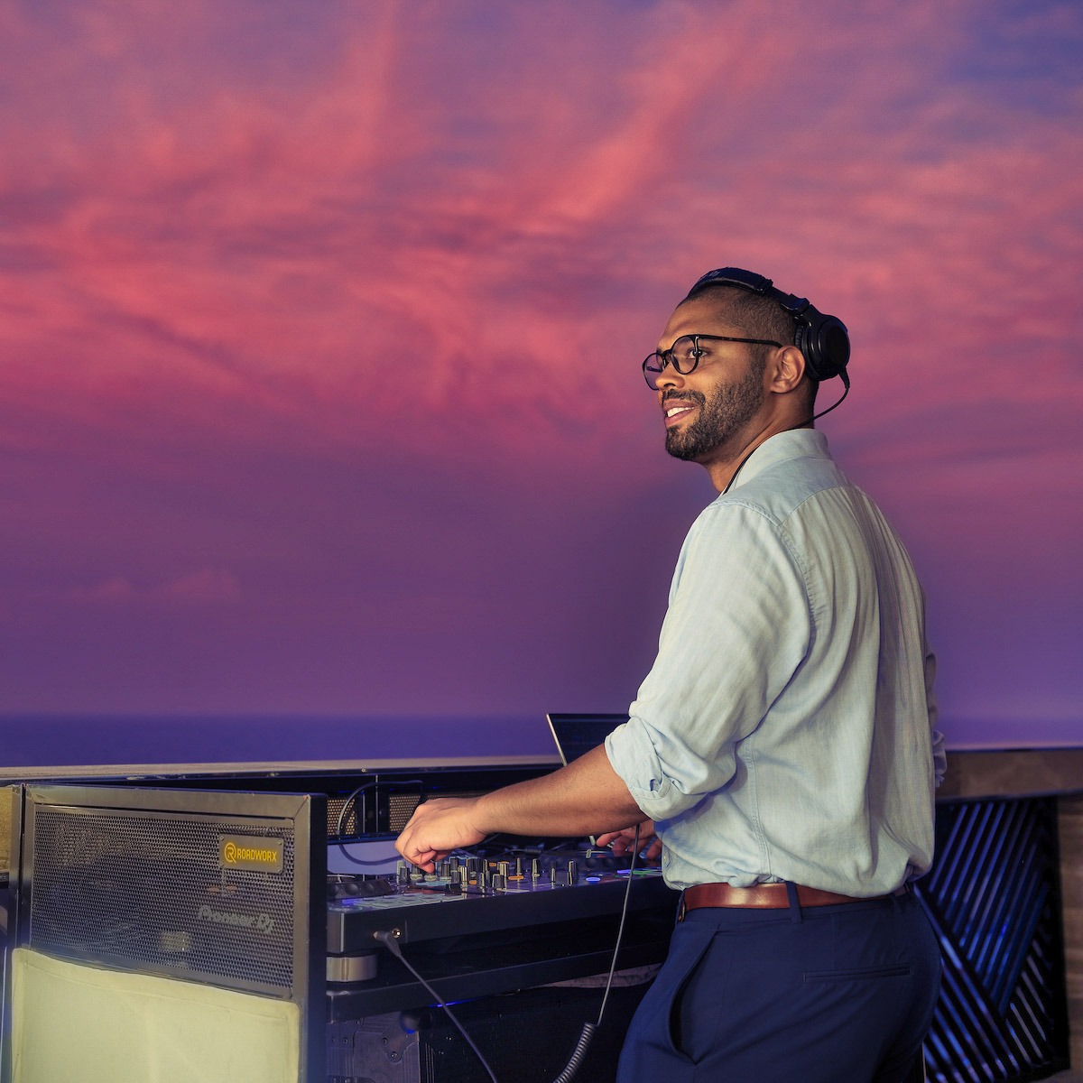 DJ playing a set on the decks of Explora one at twilight. Beautiful sky behind him